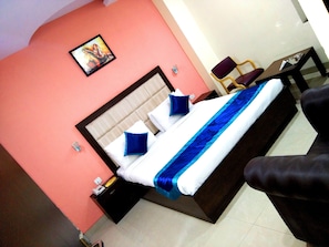 A hotel room with a bed, a nightstand, a chair, and a table.