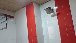 A bathroom with white and red tiled walls, a metal handrail, and a ventilation grille. - Hotel RTS Plaza Near IGI Airport (New Delhi)