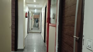 A long, narrow hallway with doors on both sides, some with red frames. - Hotel RTS Plaza Near IGI Airport (New Delhi)