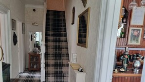 A hallway with a checkered floor, a staircase, a mirror, a sign, and a bar area with bottles and glasses. - Bryn Coed Guest House (Colwyn Bay)