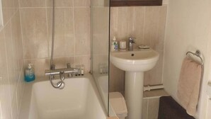A bathroom with a bathtub, a sink, and a mirror. - Bryn Coed Guest House (Colwyn Bay)