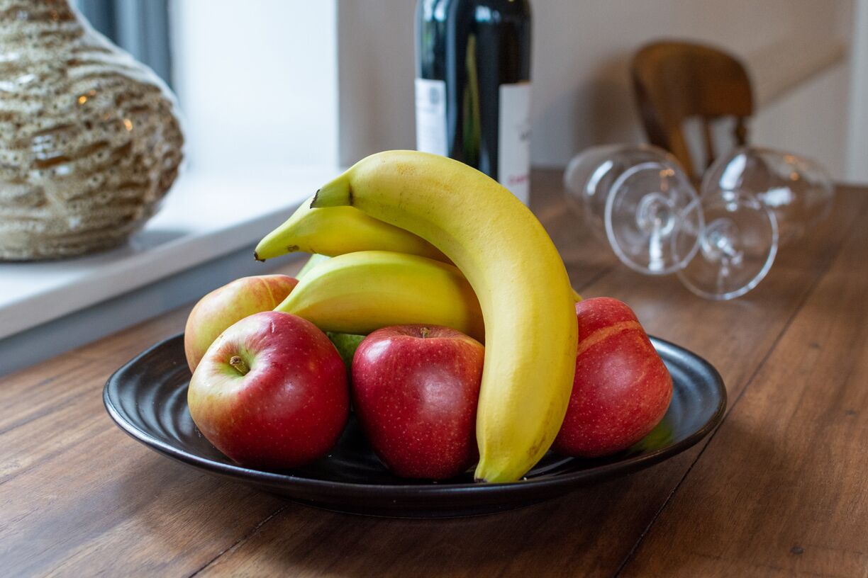 A plate with bananas and apples on a wooden table.