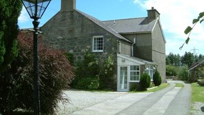 A stone house with a small porch and a window. - Cefn Uchaf Guesthouse (Garndolbenmaen)