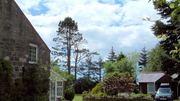 A stone building with a gravel driveway, a parked car, and surrounding greenery. - Cefn Uchaf Guesthouse (Garndolbenmaen)