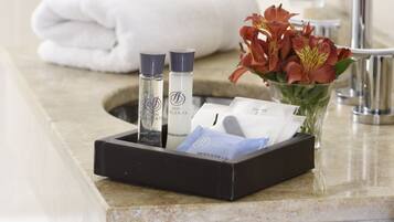 A bathroom counter with toiletries, a towel, and a vase of flowers.