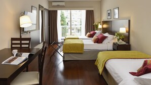 Habitación de hotel con dos camas, un escritorio, una silla, un televisor y una ventana con cortinas.