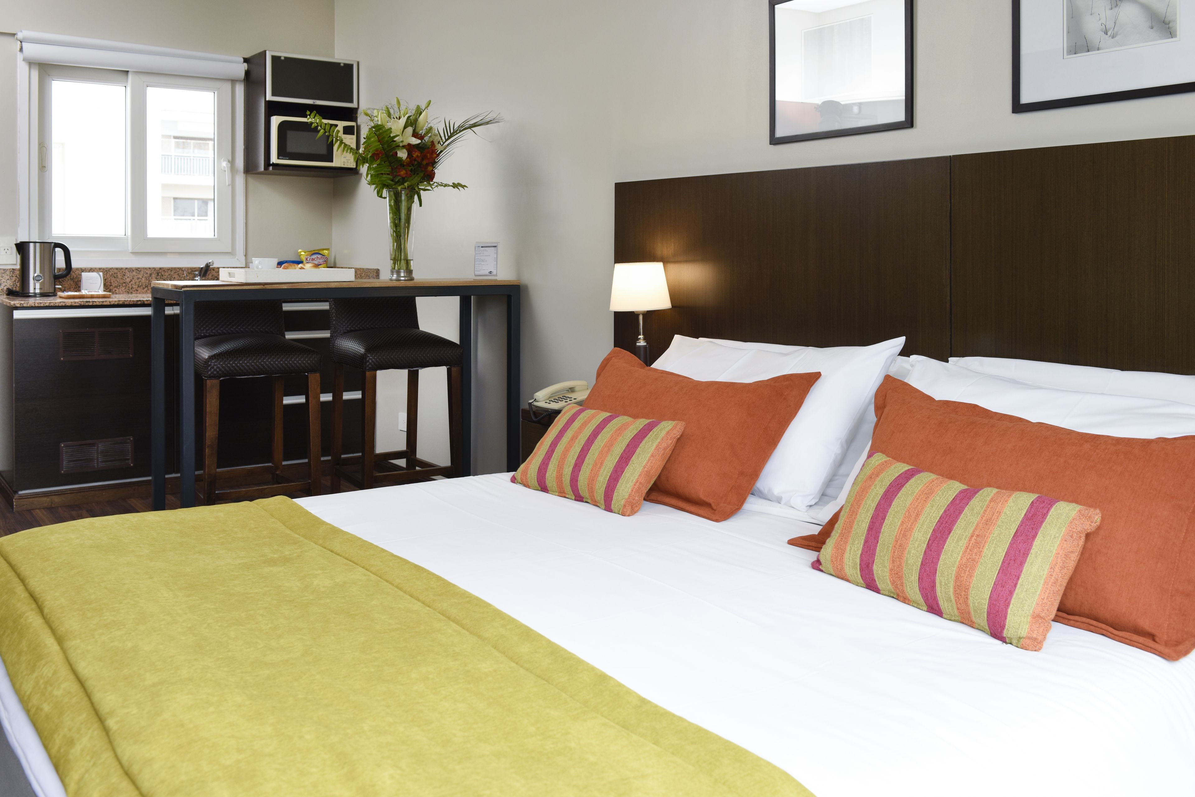 Una habitación de hotel con cama, escritorio con silla, microondas y teléfono.