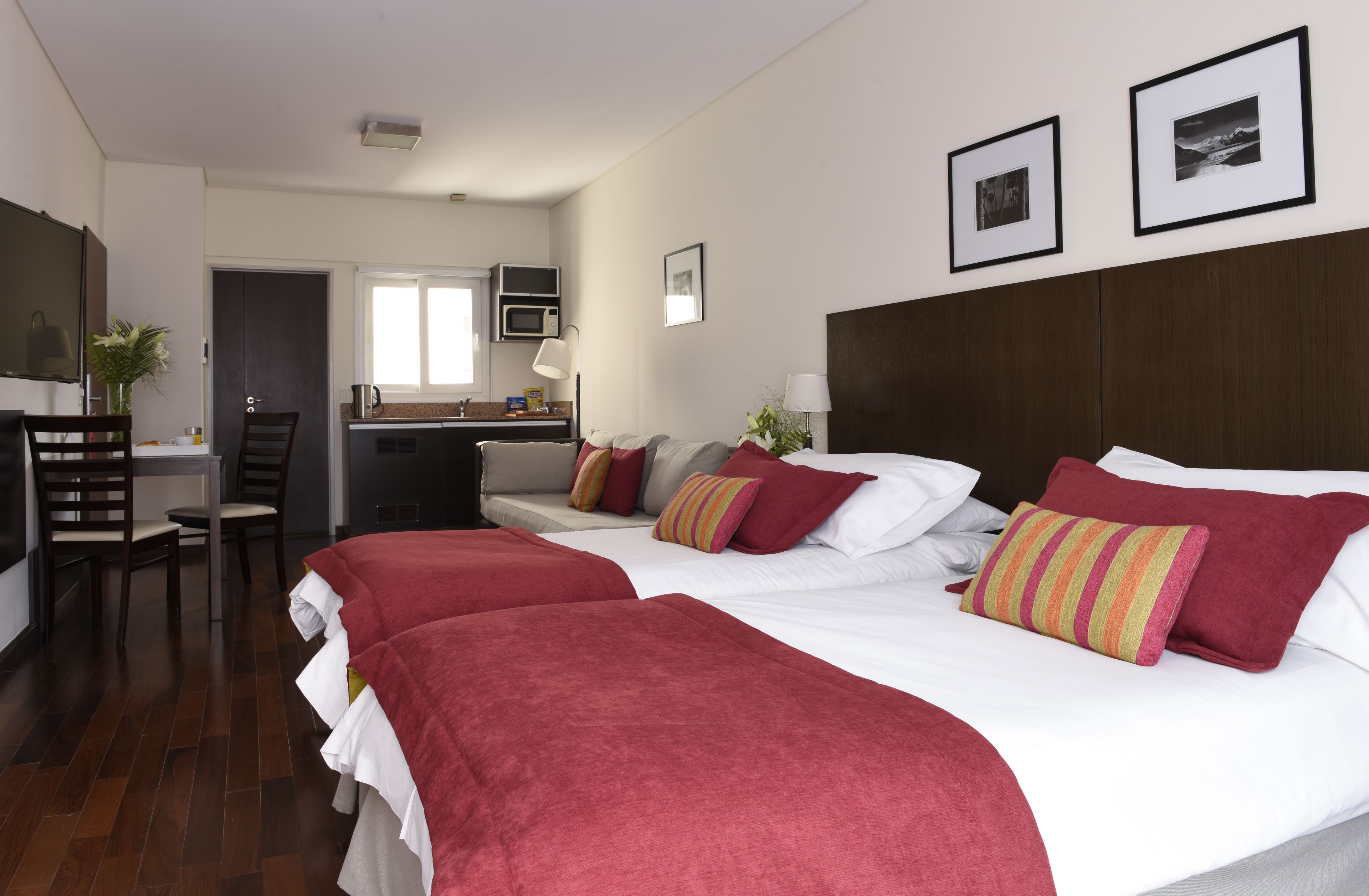 Una habitación de hotel con una cama grande, un escritorio, una silla, un microondas y una kitchenette pequeña.