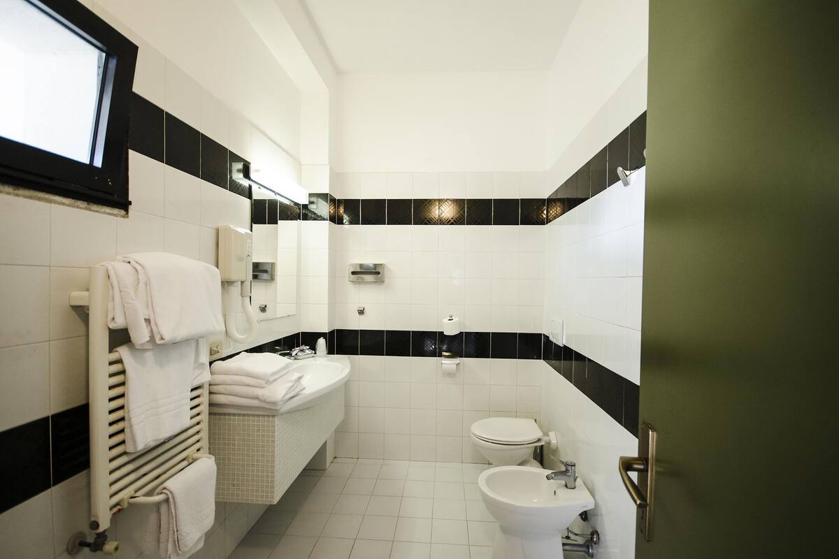 A bathroom with a white sink, a toilet, a bidet, and a towel rack.
