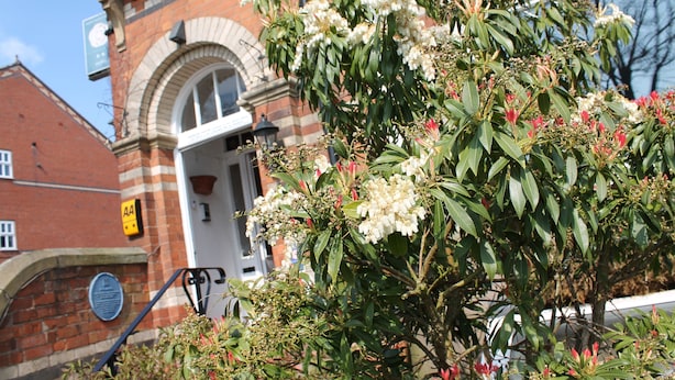 A building with a brick facade, a large arched window, and a door. - Longview Hotel (Knutsford)