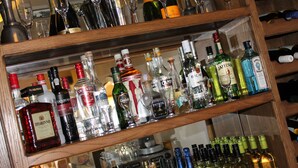 A bar area with shelves stocked with various bottles of alcohol and glasses. - Longview Hotel (Knutsford)