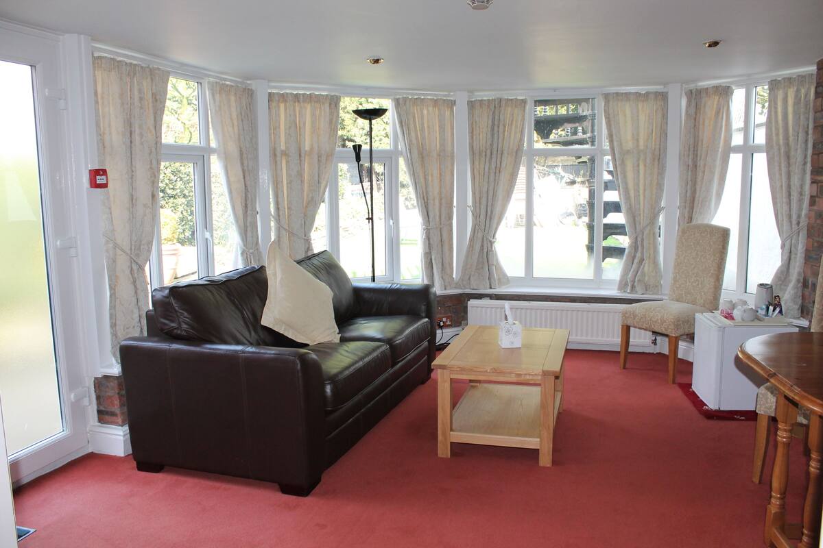 A living room with a black leather sofa, a wooden coffee table, and a white radiator.