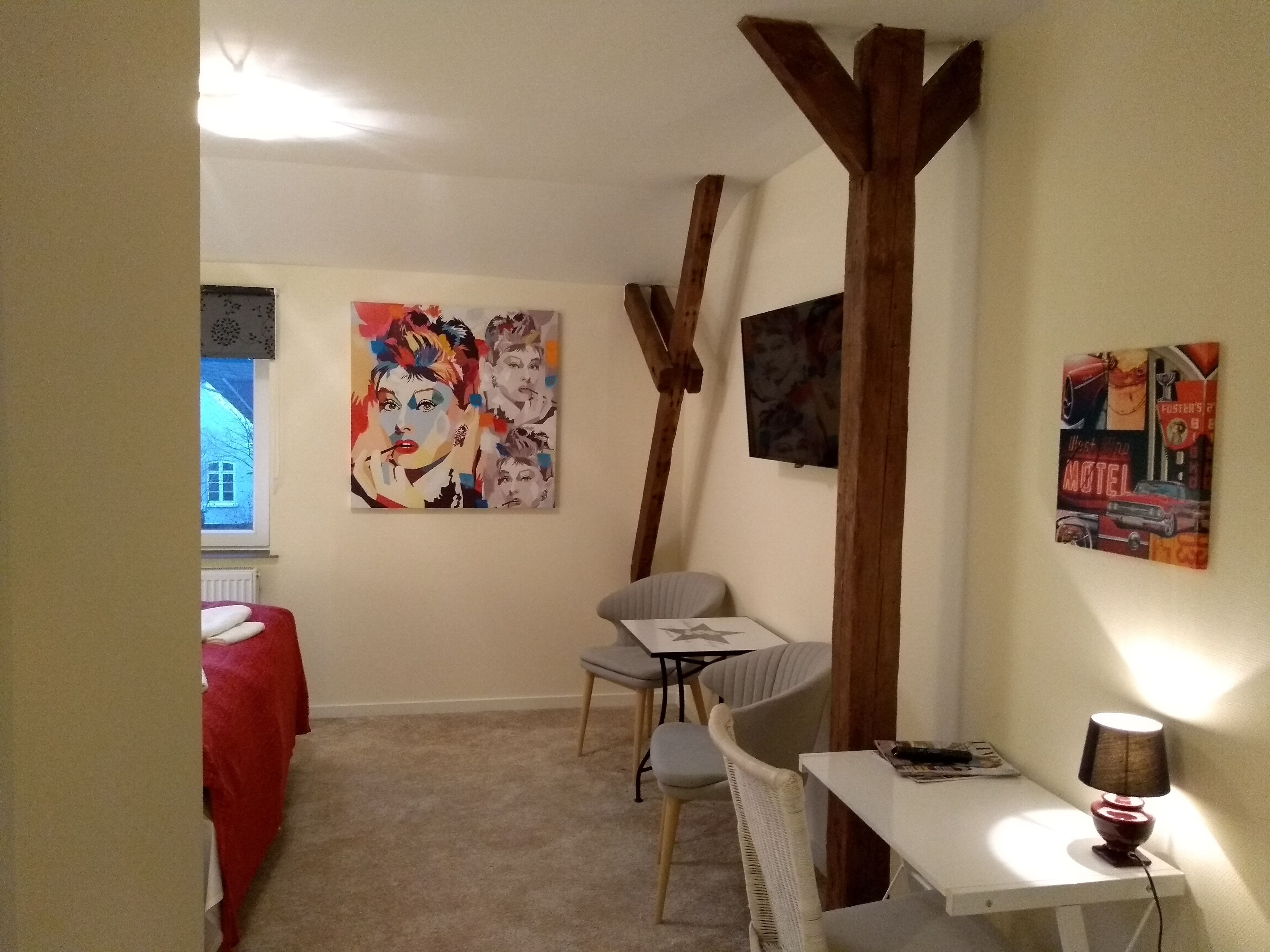 Una habitación con una mesa de comedor, sillas, un sofá rojo y obras de arte en las paredes.