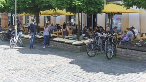 An outdoor café with tables and chairs under yellow umbrellas, surrounded by trees and bicycles. - Hotel Frøslev Kro (Padborg)