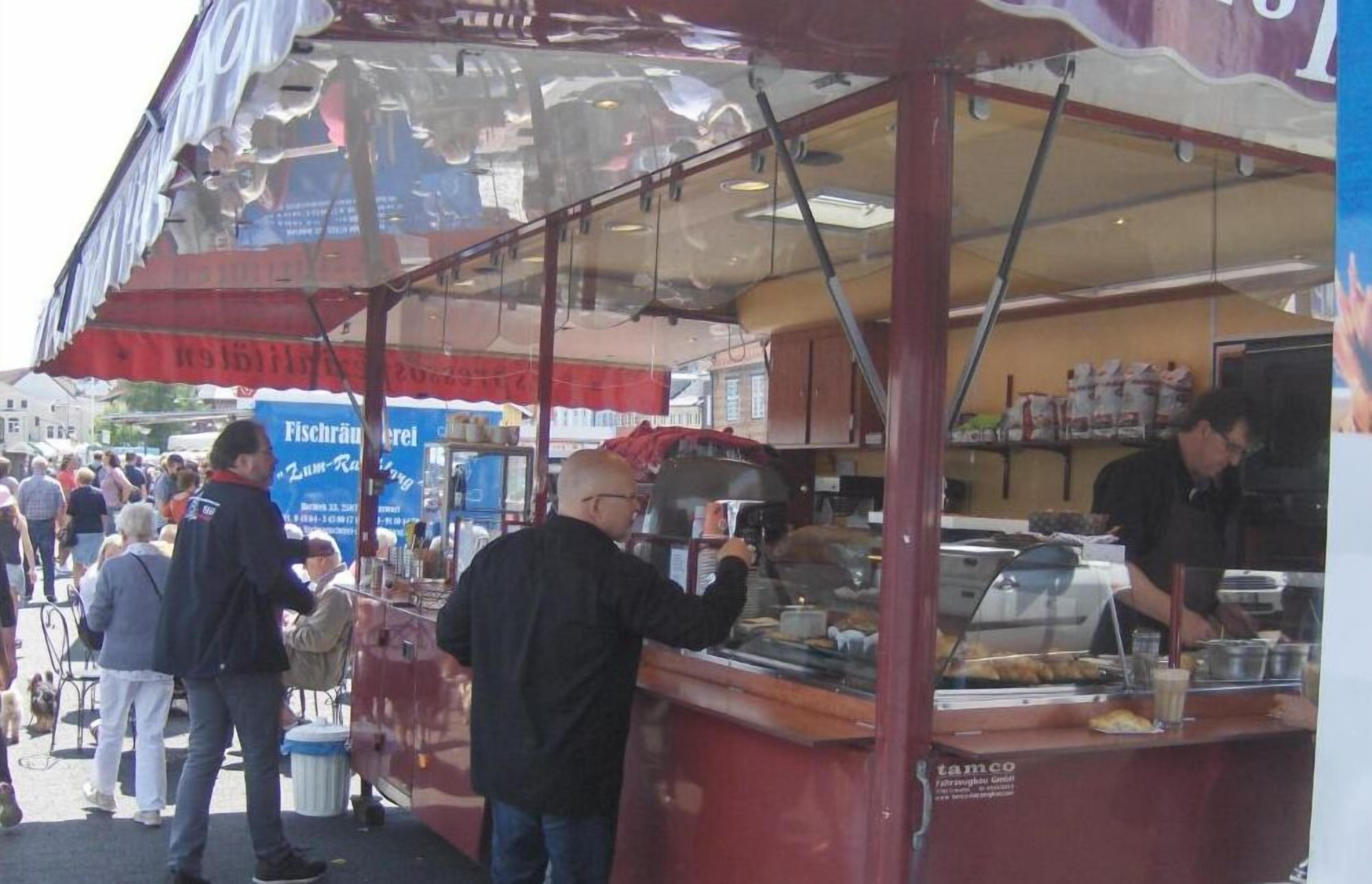 A food stall with a glass enclosure, serving food to customers.