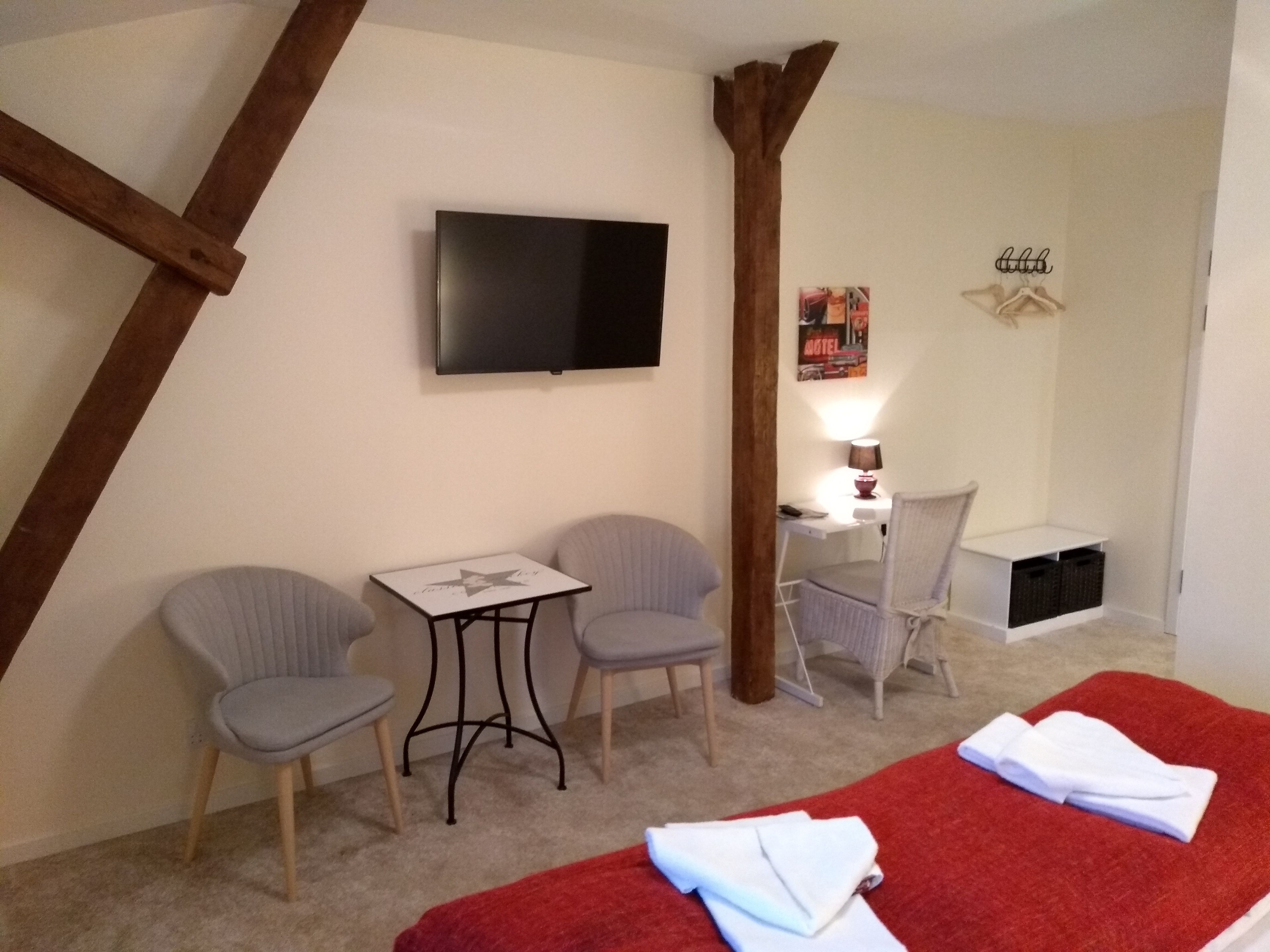 Une chambre d’hôtel avec deux lits simples, un bureau avec une chaise, une petite table et deux fauteuils.