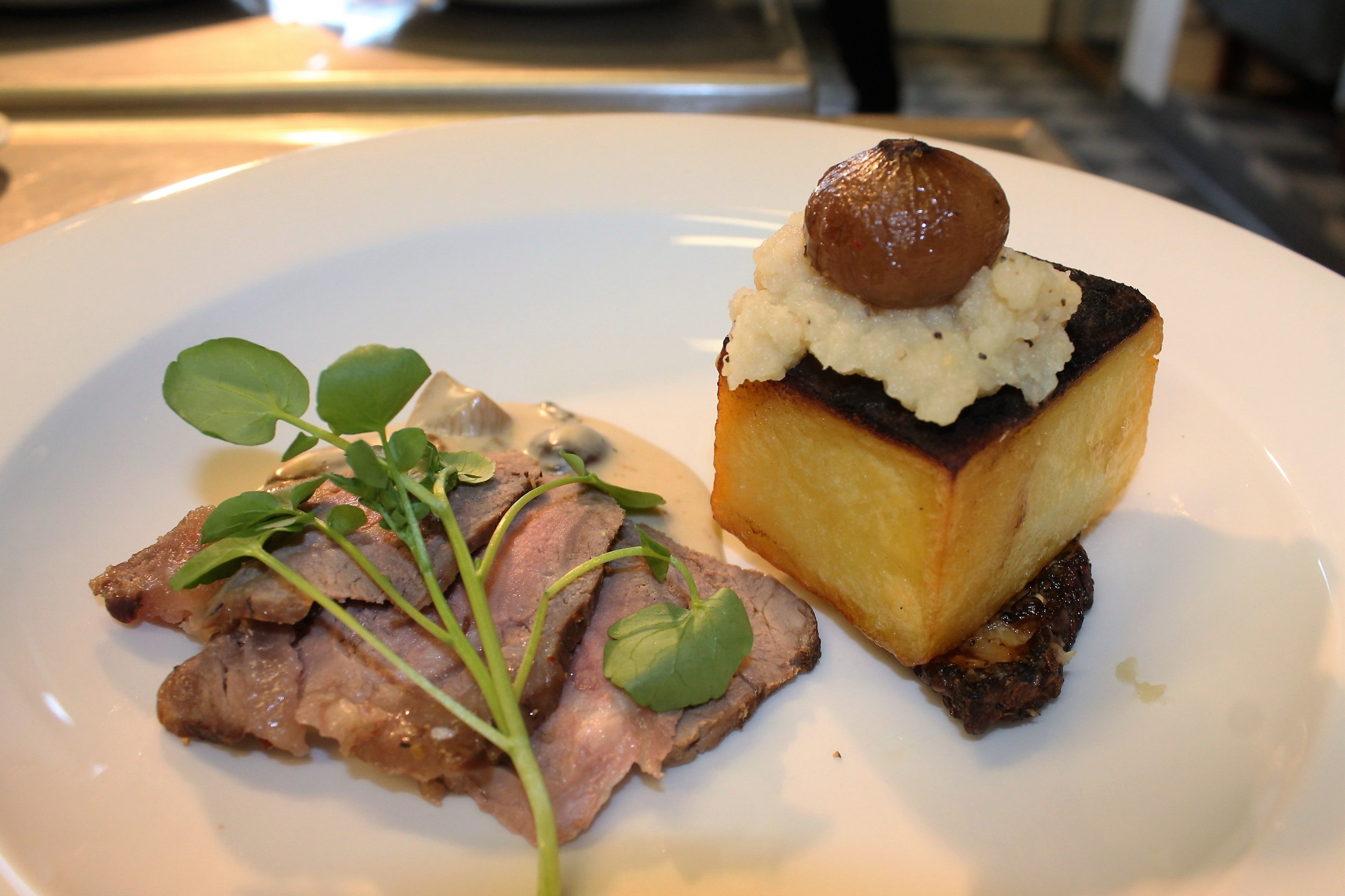 Une assiette avec de la viande tranchée et un plat carré sur lequel repose un champignon.