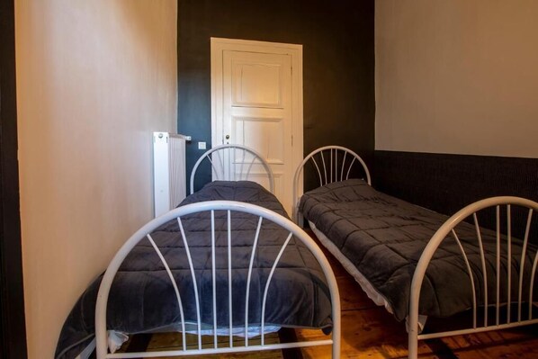 Una habitación con dos camas individuales, un radiador blanco y una puerta.