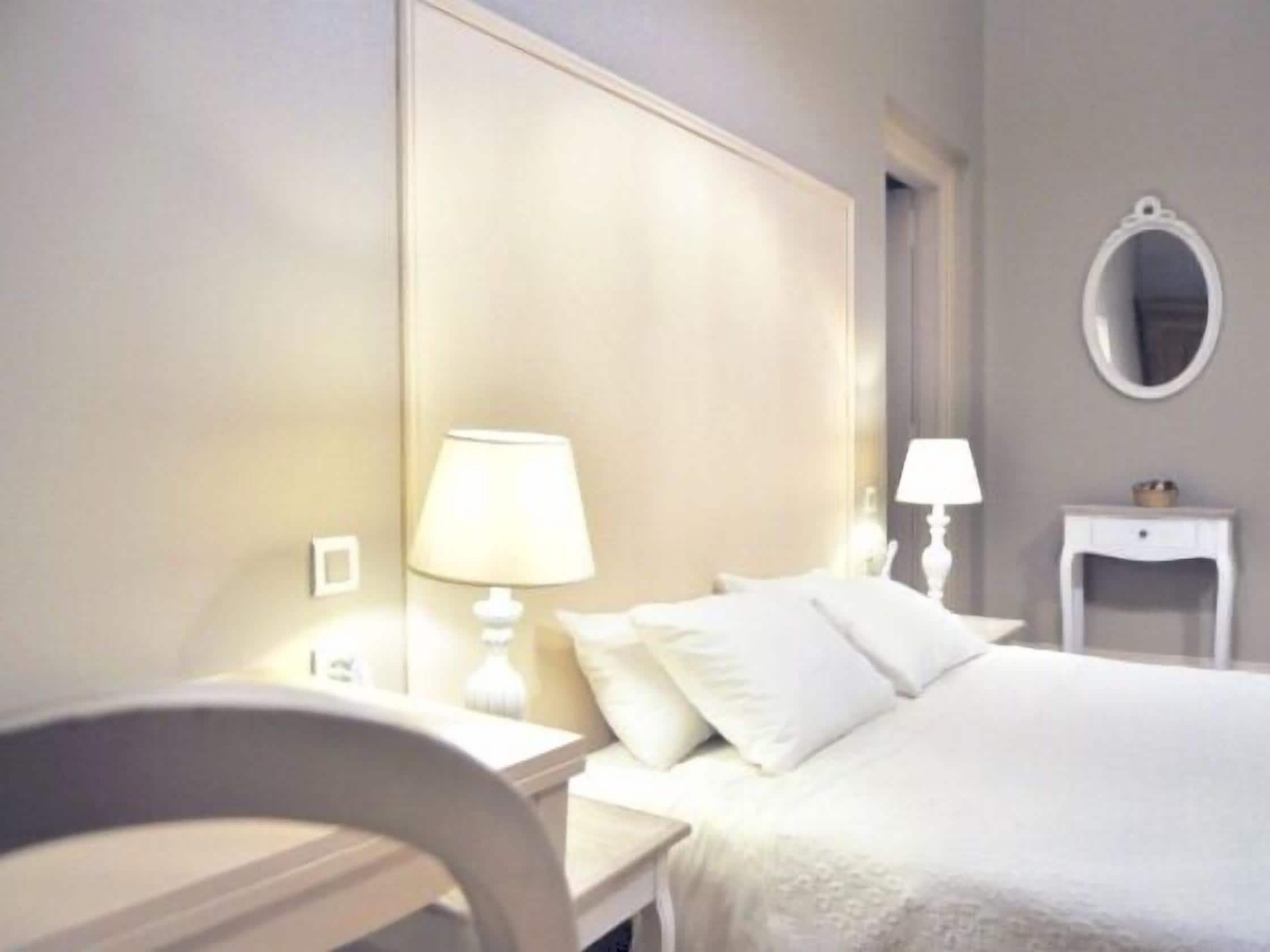 A hotel room with a bed, two bedside tables, a lamp on each table, and a mirror on the wall.