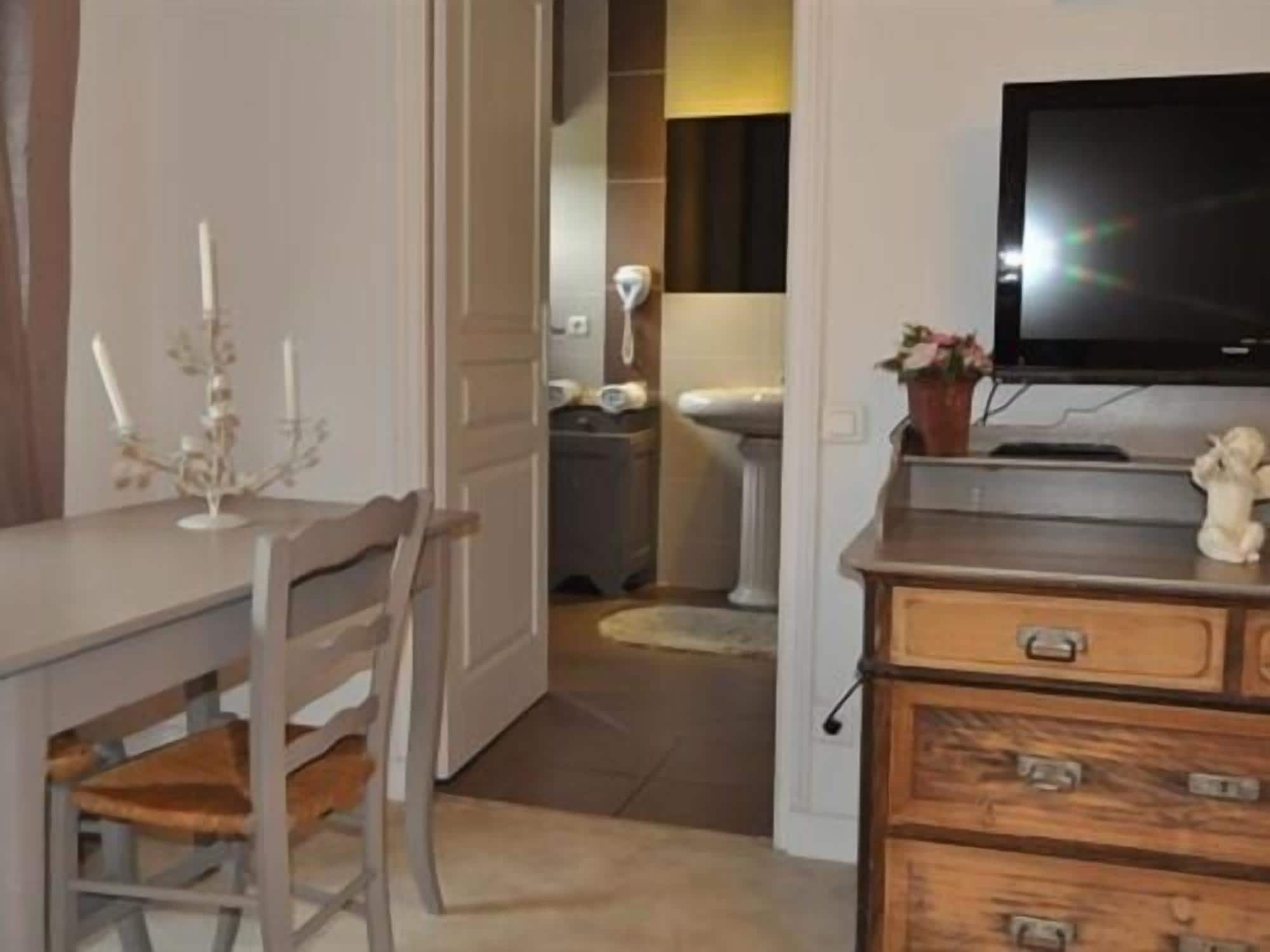 A room with a wooden dresser, a television on top, a small statue, and a door leading to another room.