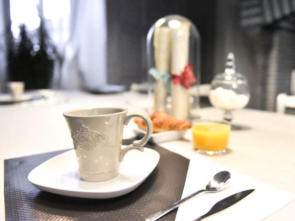 Ein Frühstückstisch mit einer Tasse, einem Glas Orangensaft und einem Teller Croissants.
