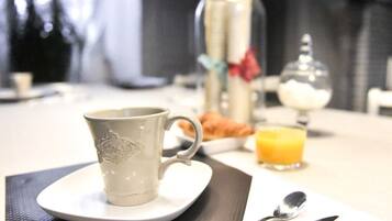 A breakfast setting with a cup, a glass of orange juice, and a plate of croissants.