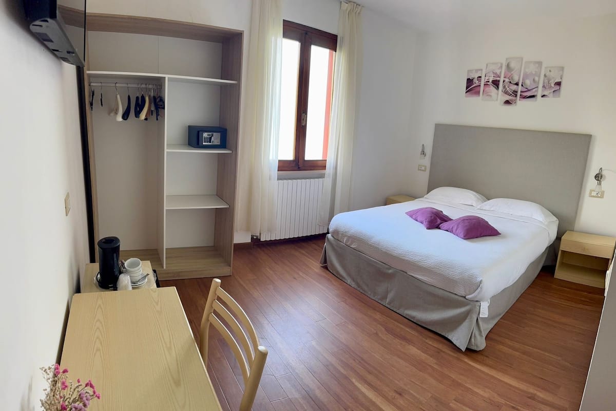 Quarto com cama, escrivaninha, cadeira, guarda-roupa e radiador.