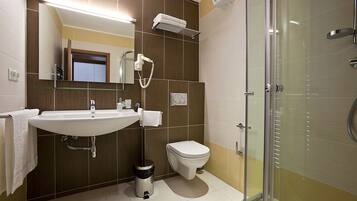 Un baño moderno con lavamanos, inodoro y cabina de ducha con mampara de vidrio.
