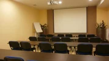 A conference room with a long table and chairs, a projector screen, and a whiteboard.