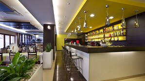 Een moderne bar met een lange toonbank, meerdere barkrukken en hangende verlichting.