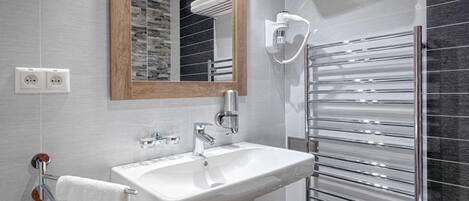 Un baño moderno con un lavamanos blanco, un espejo, un perchero y una toalla colgada.