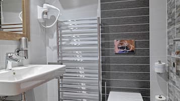 Un baño moderno con lavamanos empotrado, cabina de ducha con mampara de cristal y retrete.