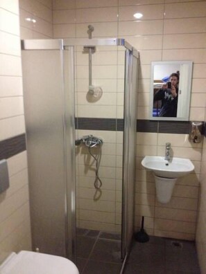 A bathroom with a glass-enclosed shower, a sink, and a mirror.