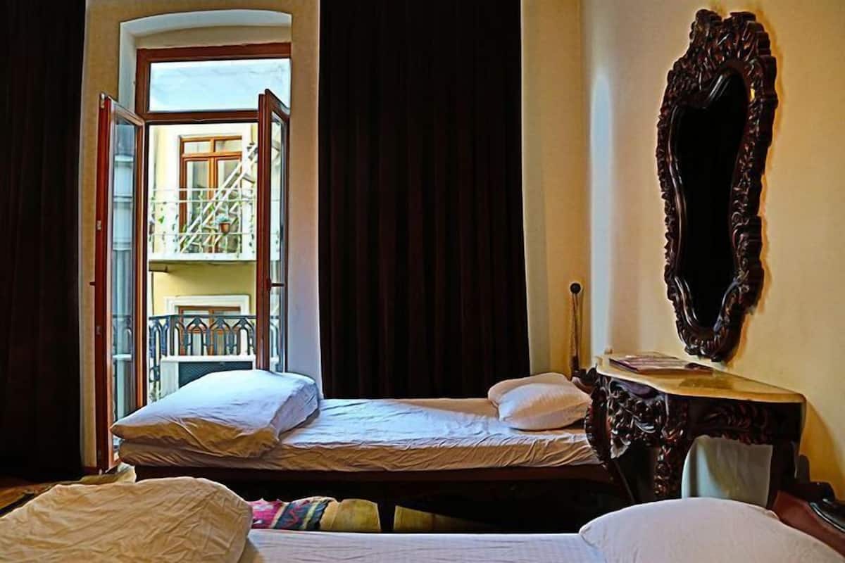 A hotel room with a bed, a mirror, and a view of a balcony.