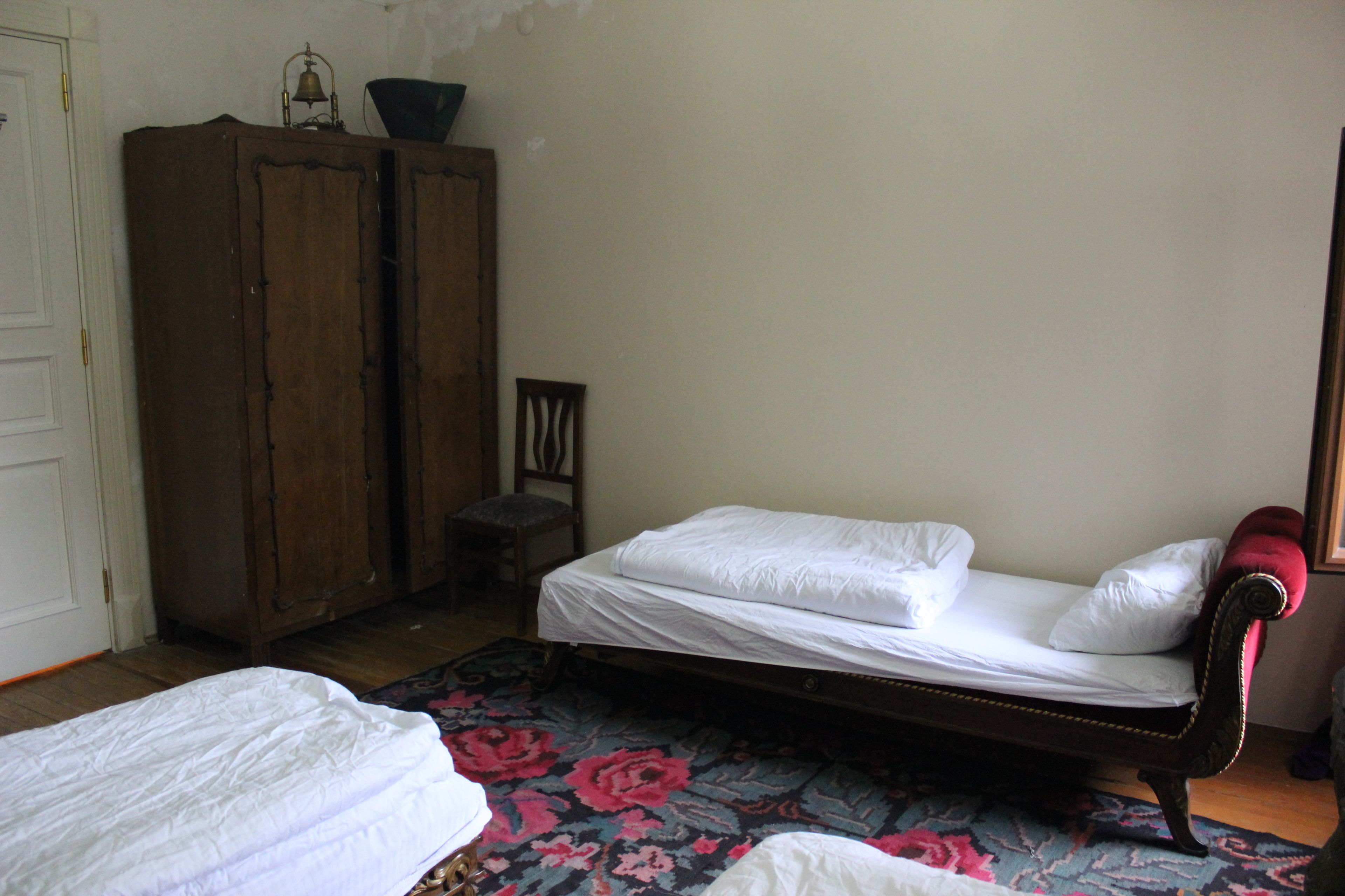 Ein Schlafzimmer mit einem Einzelbett, einem Holzschrank und einem Stuhl.