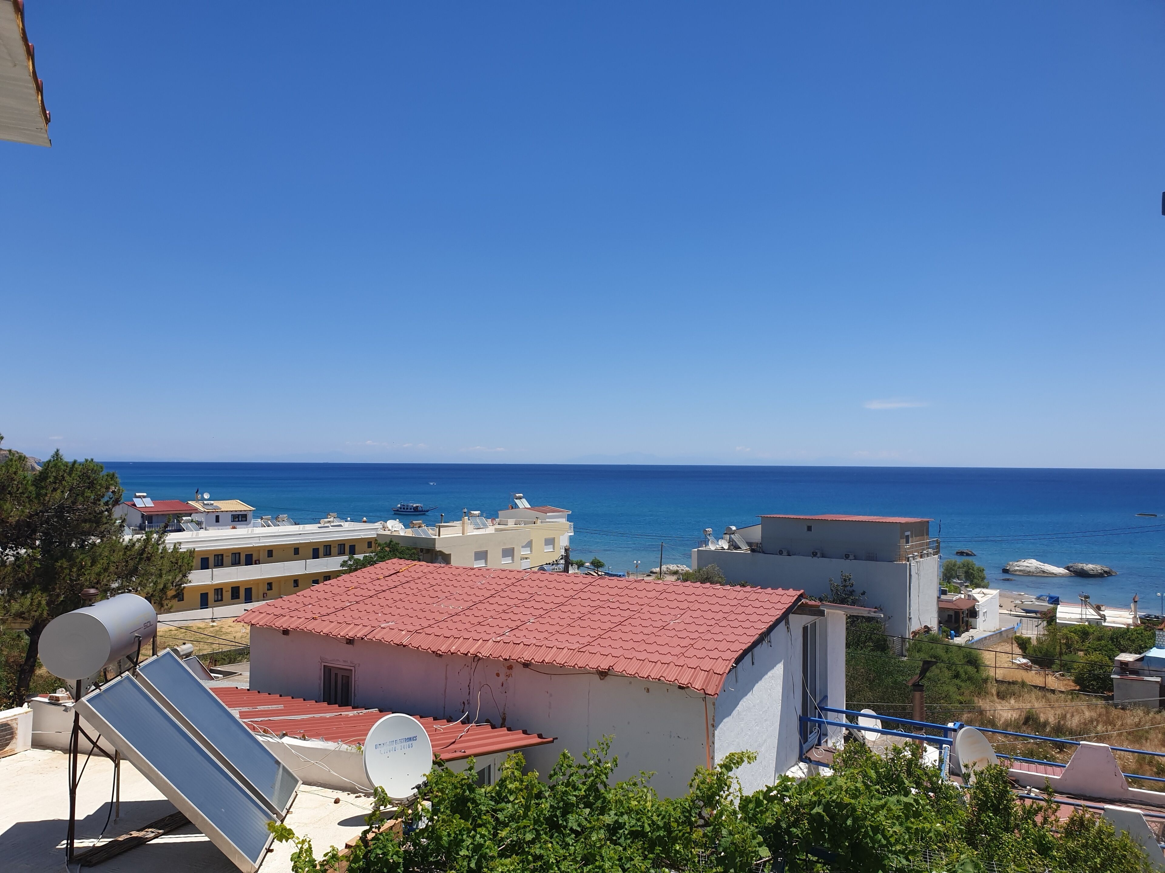 A coastal residential area with buildings, solar panels, and a clear view of the sea.