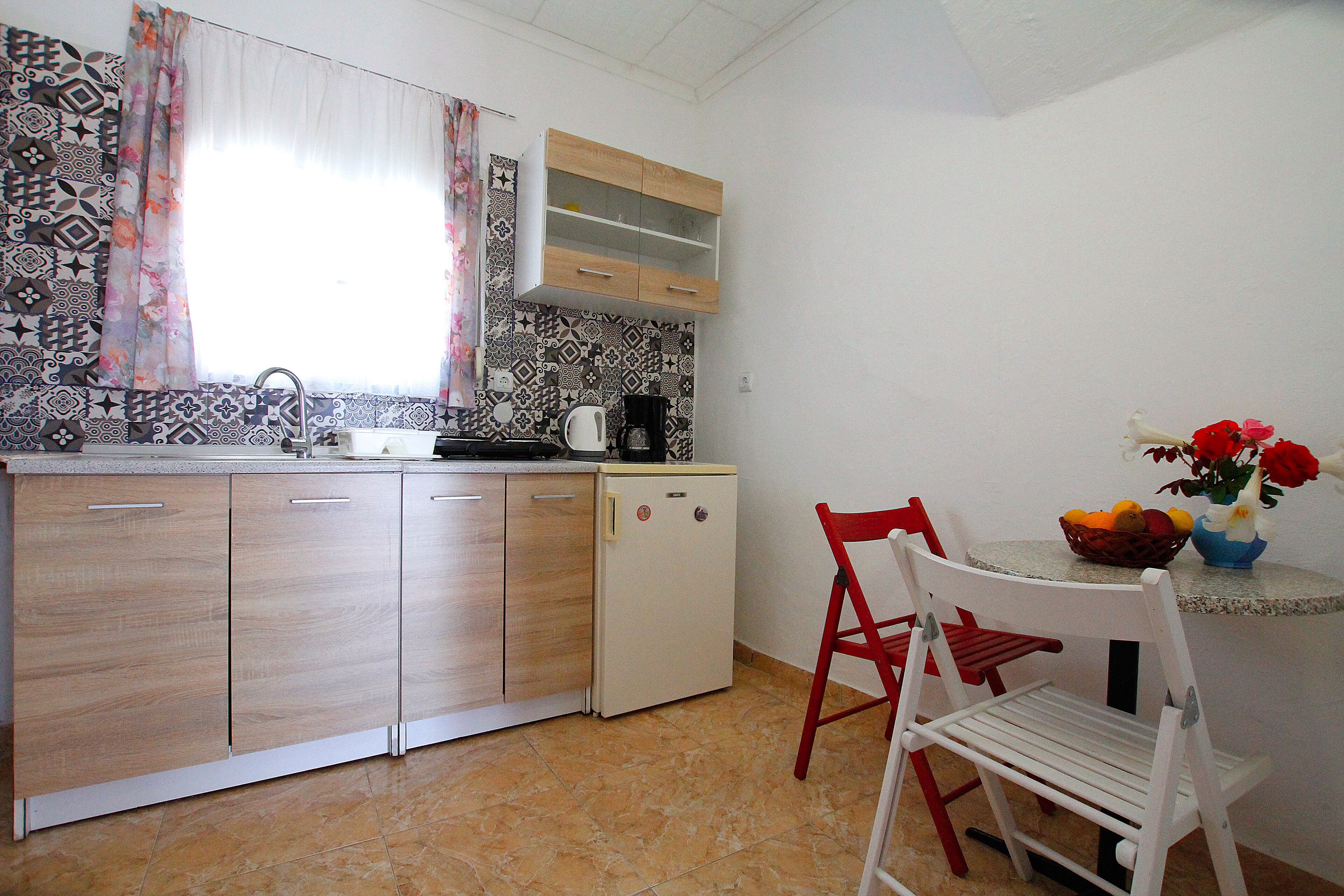 A compact kitchen with a refrigerator, a sink, and a dining area with a chair and table.