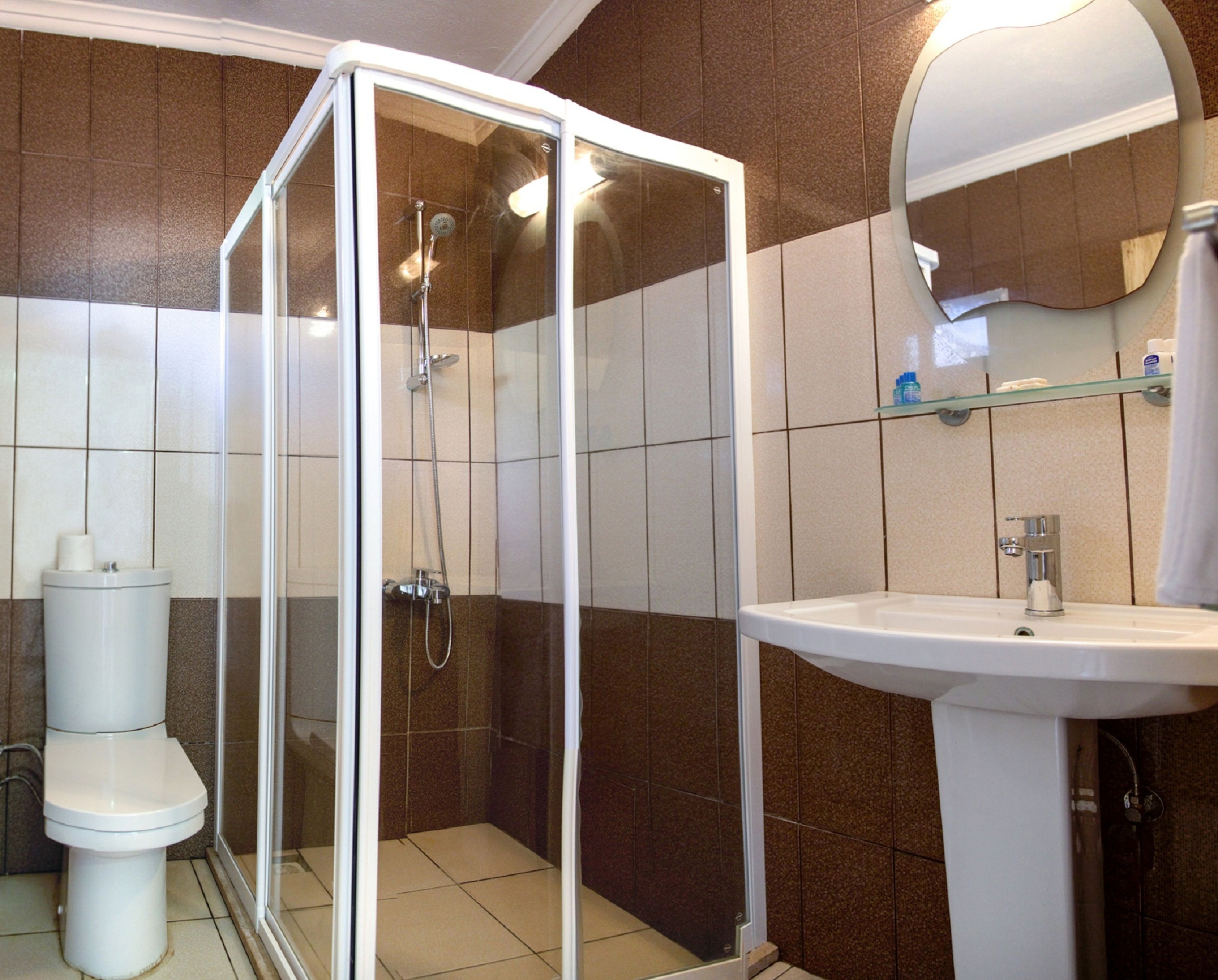 A bathroom with a glass-enclosed shower, a white sink, and a toilet.