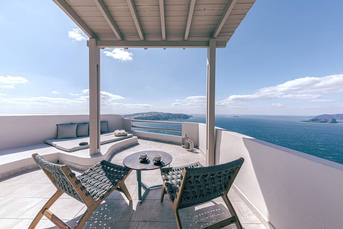 Una terraza con una mesa redonda y dos sillas de mimbre, con vistas a un paisaje marino.
