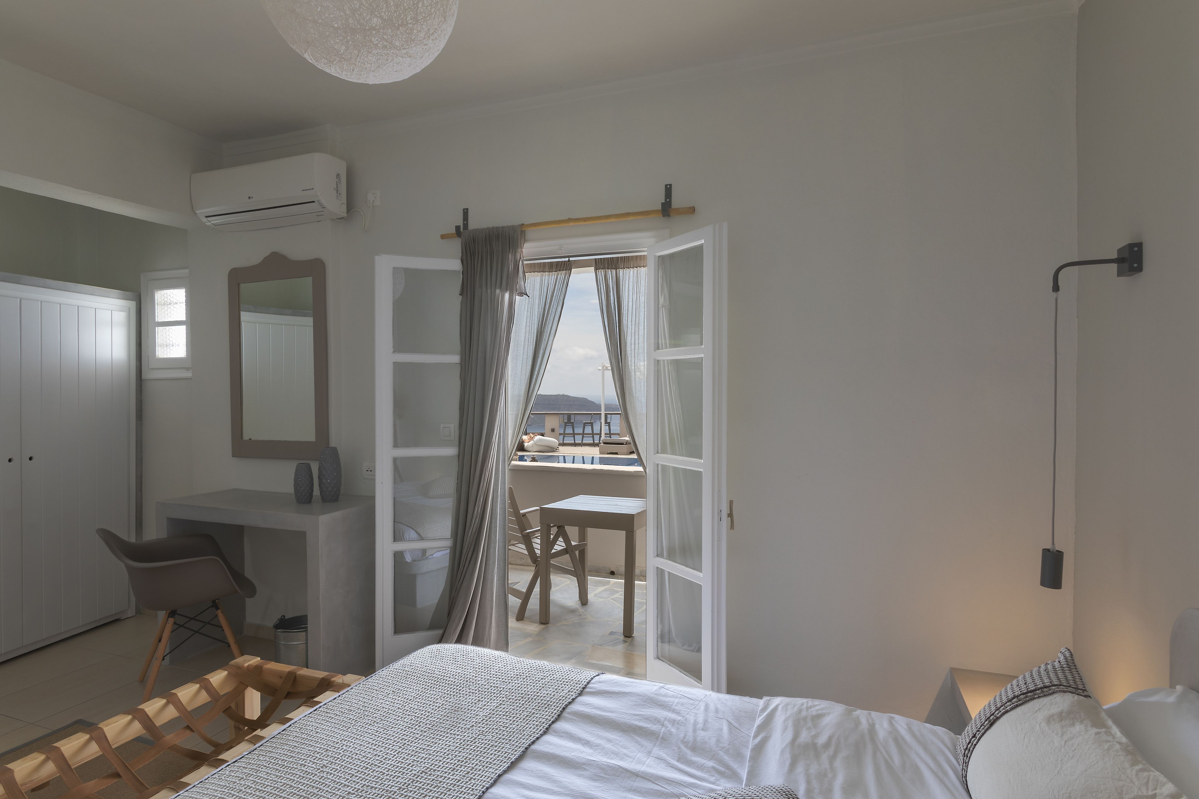 Un dormitorio con cama, mesita de noche, silla y puerta abierta que da a un balcón.