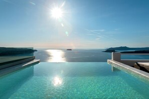 An infinity pool with clear water and a view of the sea and distant islands. - Grand View (Santorini)