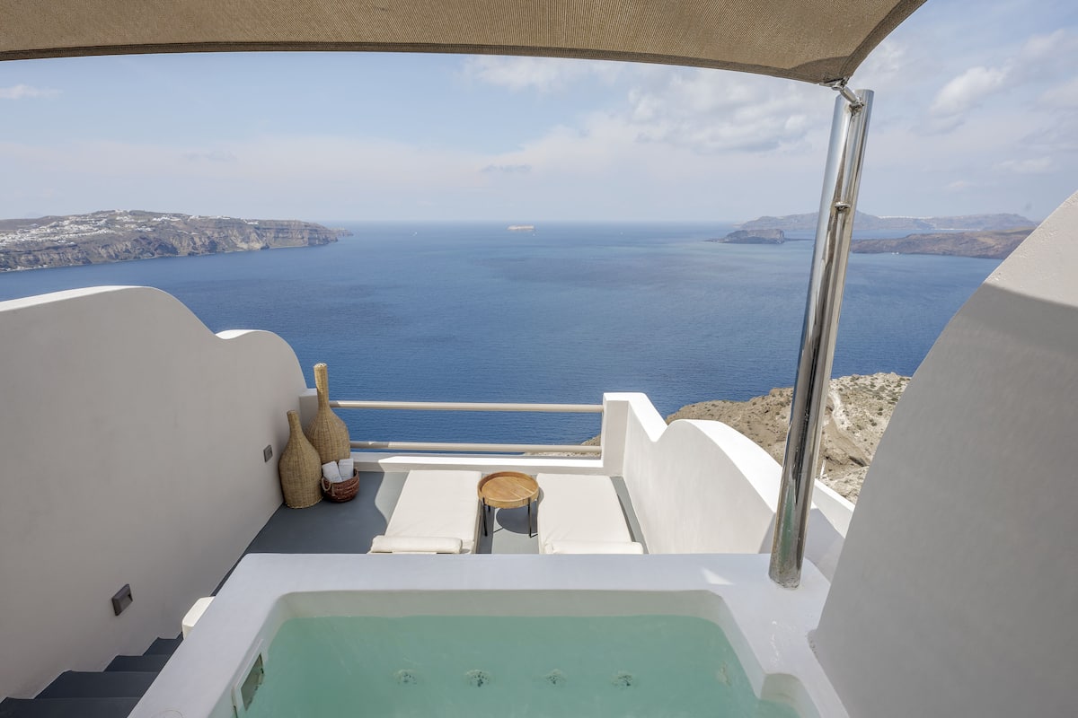 Un balcón con vista al mar, un jacuzzi y dos cestas de mimbre.
