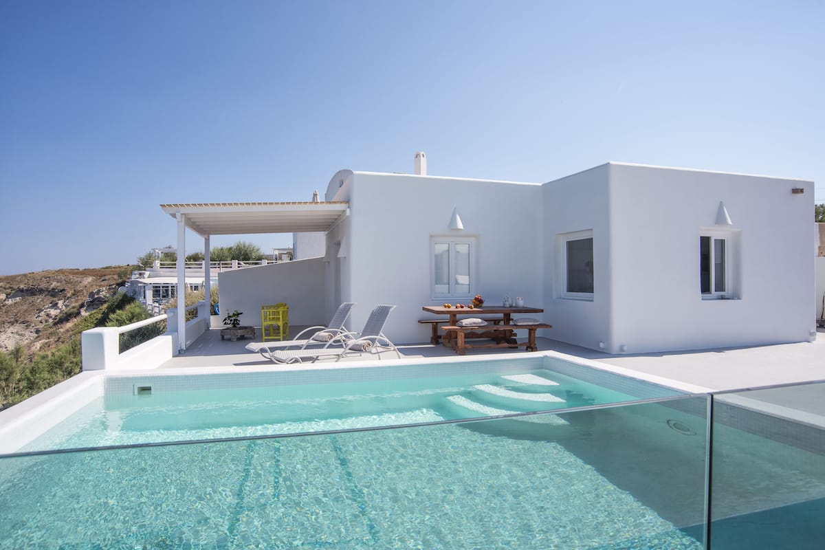 Un edificio moderno y blanco con piscina, mobiliario exterior y vistas al paisaje.