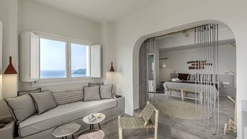 Une chambre moderne avec un canapé, deux petites tables, une chaise et un lit donnant sur une vue agréable.