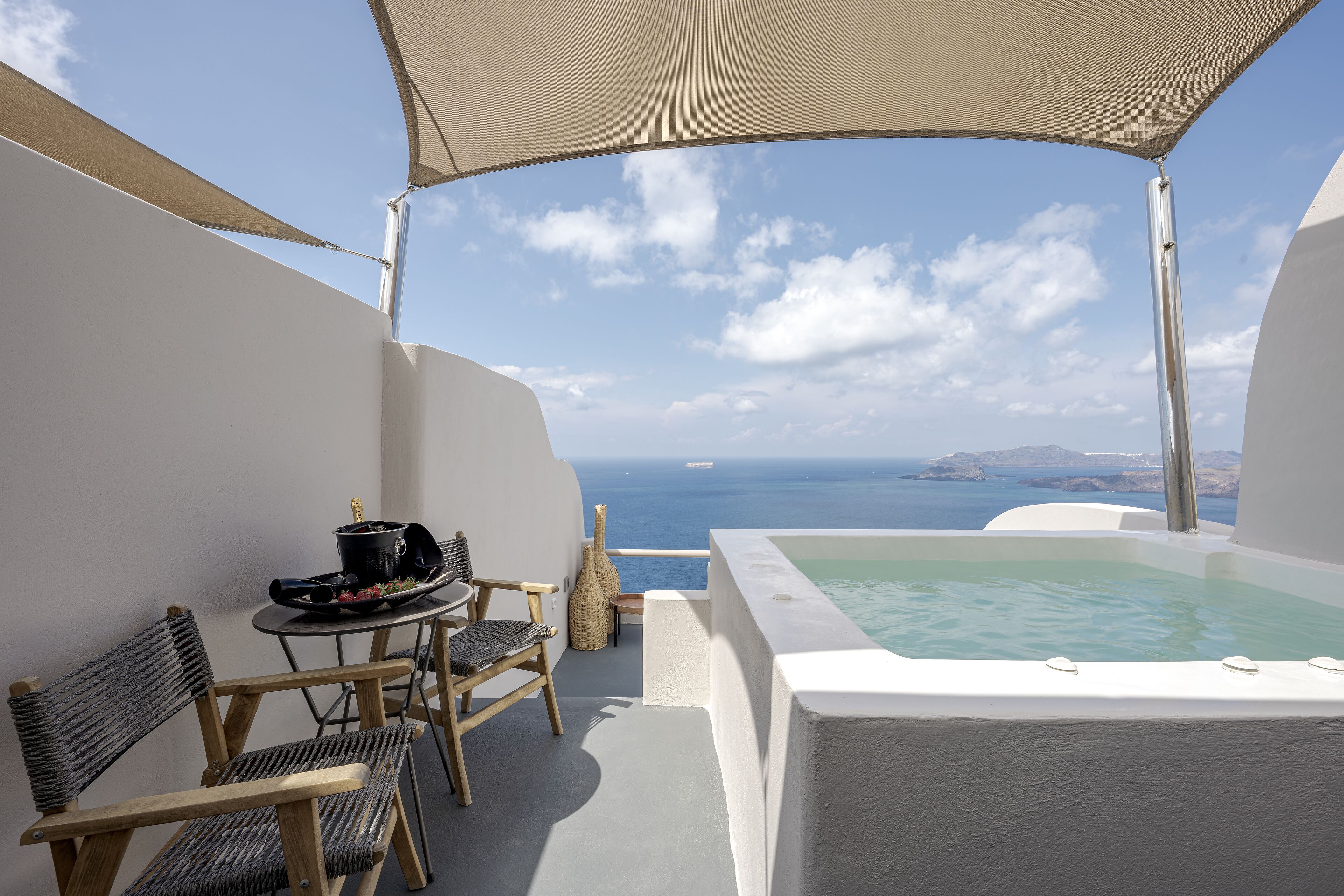 Ein Balkon mit Meerblick, einem Whirlpool und einem Tisch mit Stühlen.