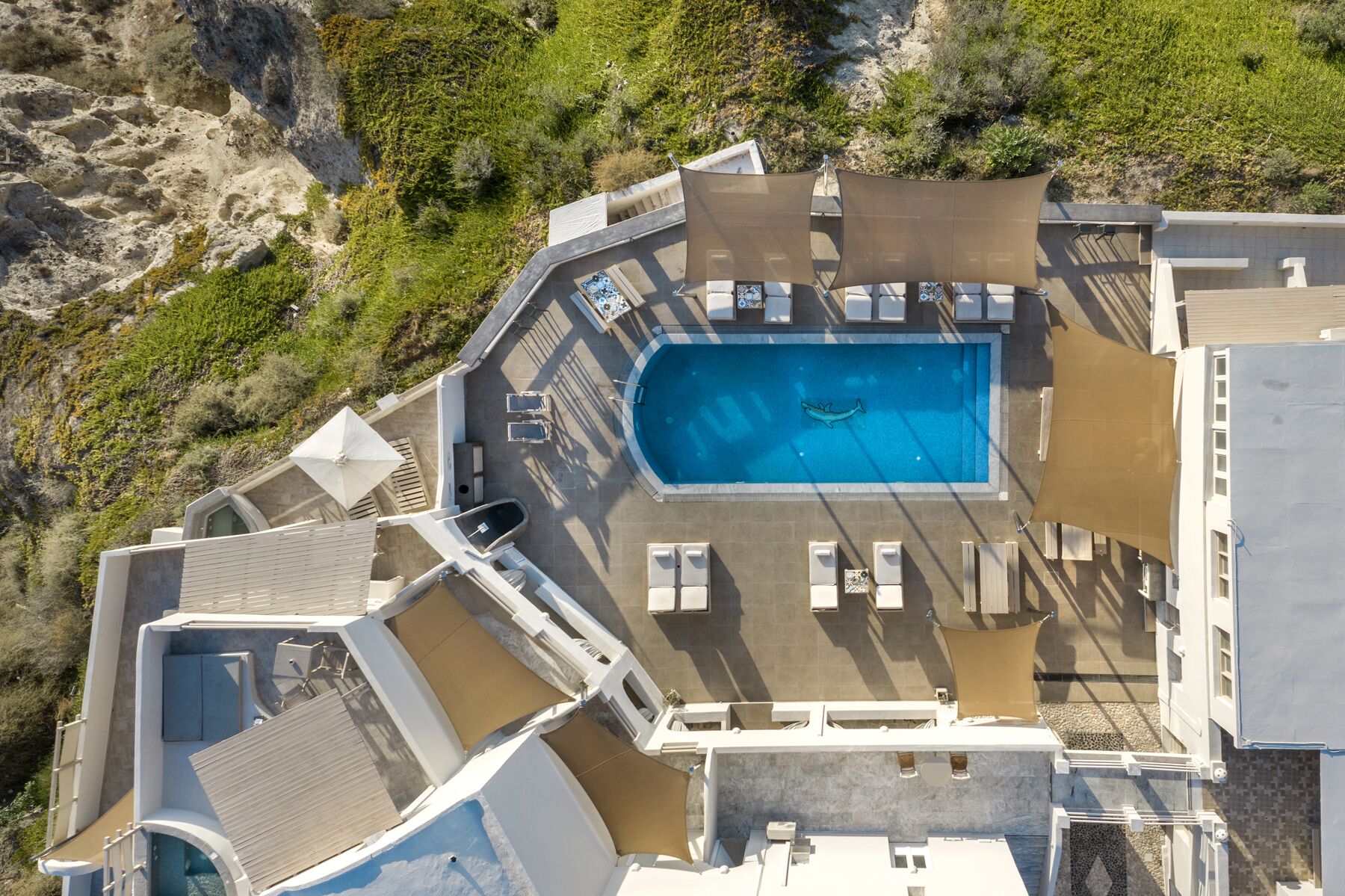 An aerial view of a resort with a swimming pool surrounded by sun loungers and a deck area.
