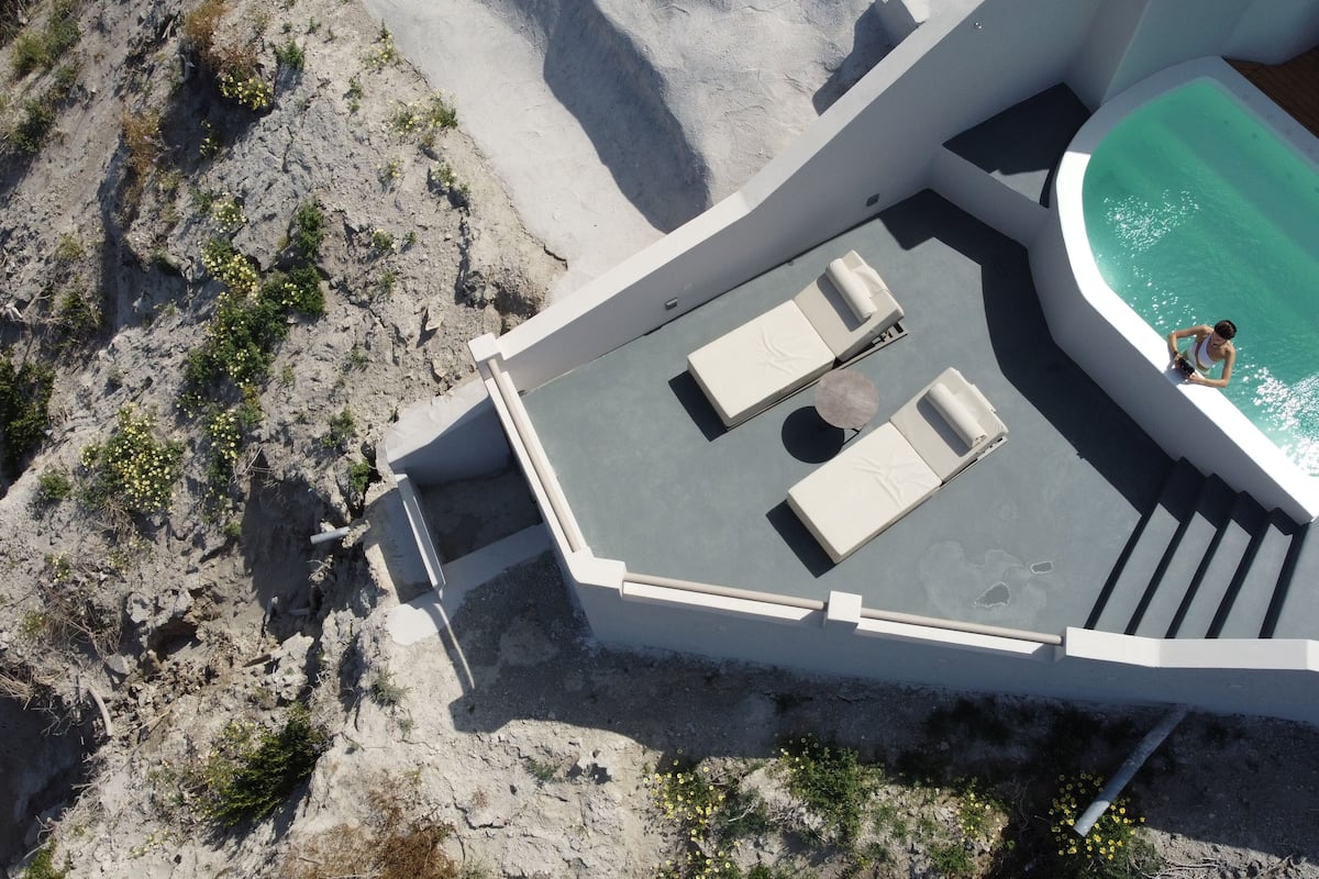 Vista aérea de un área de piscina en la azotea con un pequeño rincón de descanso y una persona relajándose junto a la piscina.