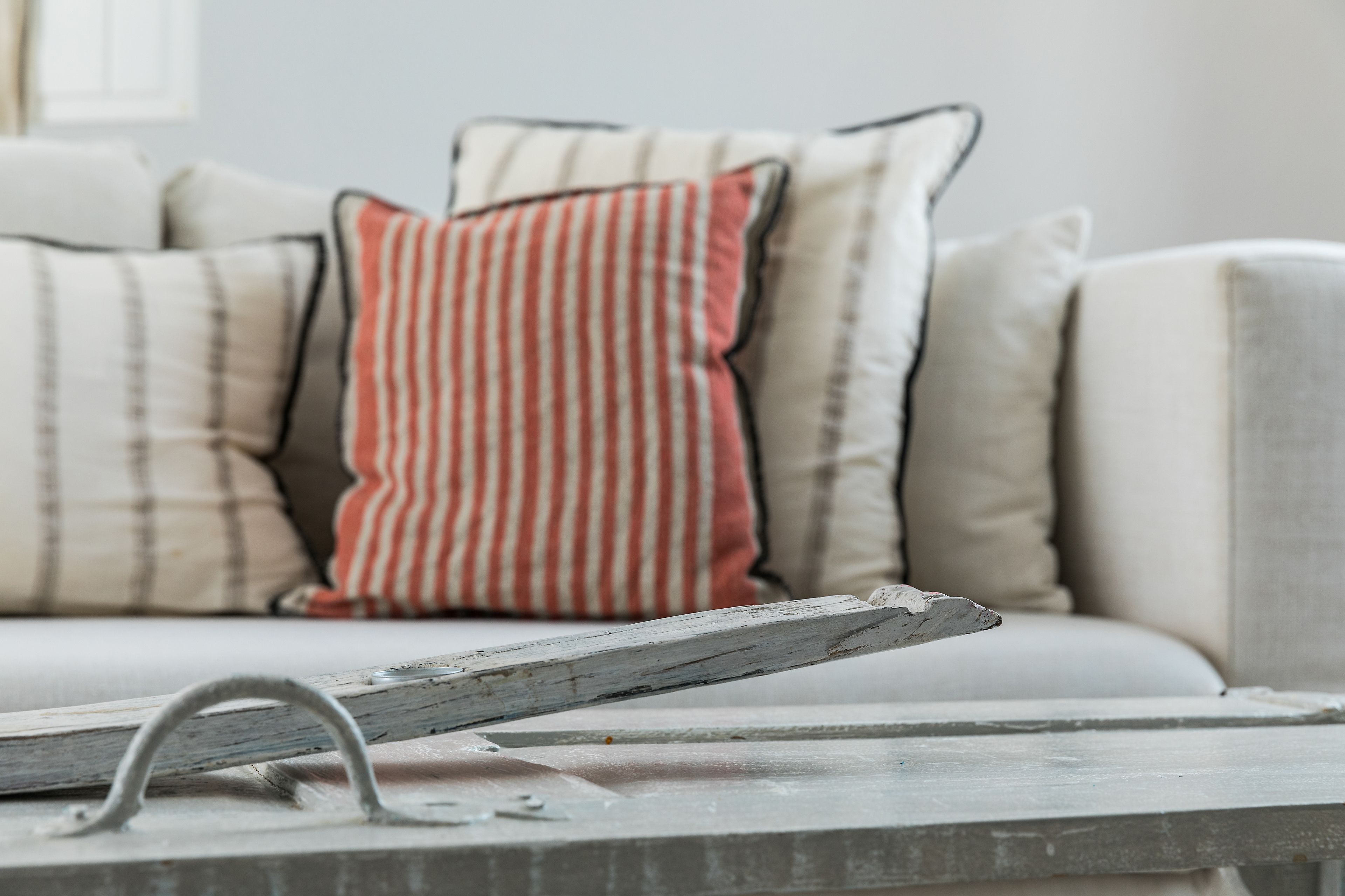 A sofa with striped pillows and a rustic metal object on a table.