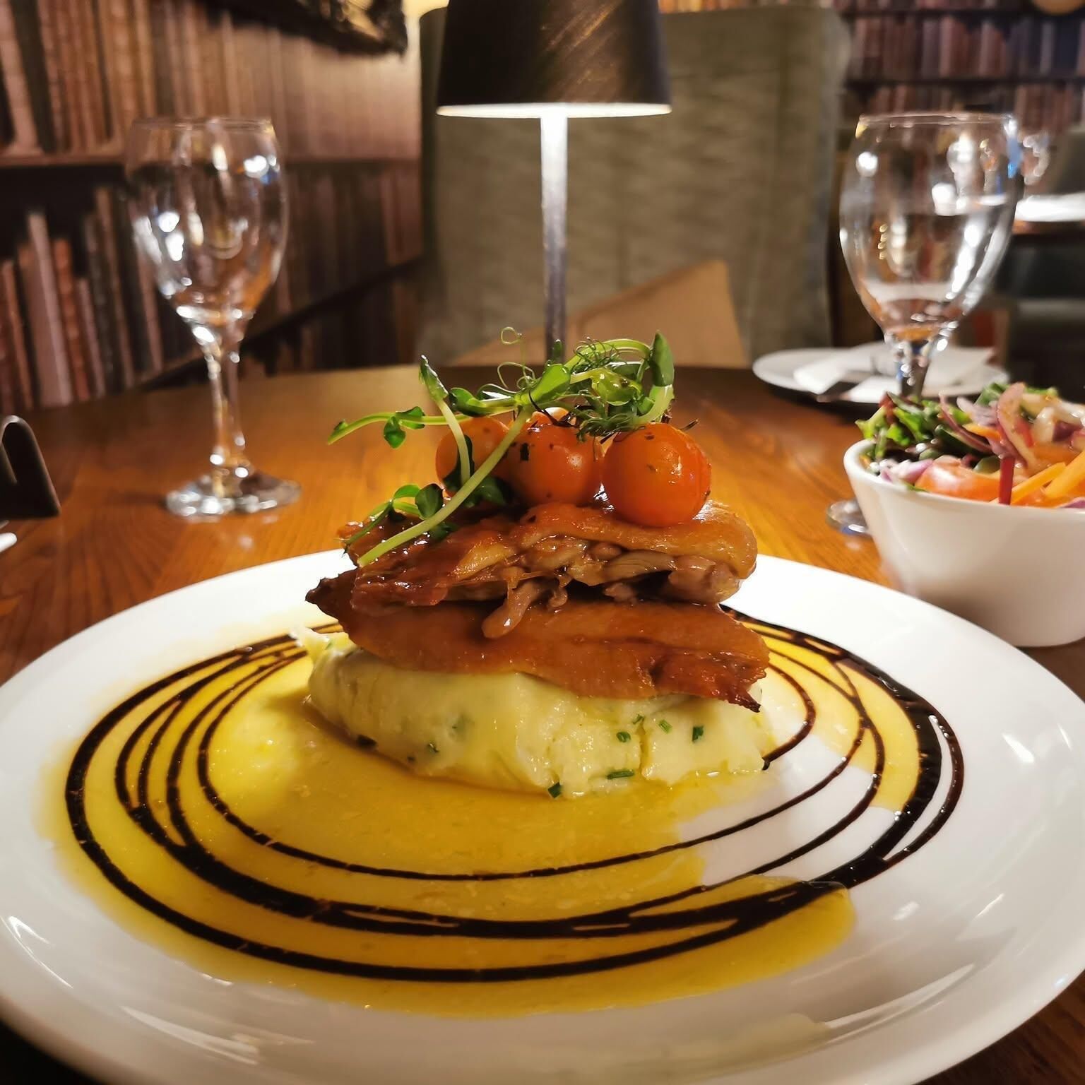 A plate of food with a sauce and garnish on a wooden table.