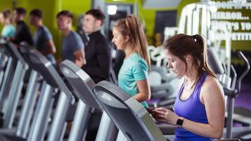 Un gimnasio con cintas de correr y equipamiento de ejercicio.